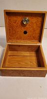 Open wooden humidor showing cedar interior and hygrometer on lid.