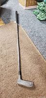Full length view of the golf putter showing metal shaft and grip.