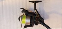 Photo of TDX 1000 fishing reel showing side view with yellow fishing line on spool and black handle.