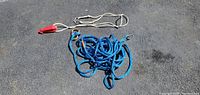 Image showing a blue braided tow rope with metal hooks and a white rope with a red stopper on end.