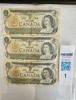Front sides of three Canadian 1 Dollar 1973 Series A banknotes showing Queen Elizabeth II portraits and denomination details