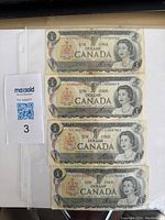 Four 1973 Canadian one dollar banknotes Series E front side, each featuring a portrait of Queen Elizabeth II and denomination text.