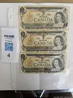 Front sides of three Canadian one dollar banknotes from 1973, series E, showing Queen Elizabeth II portraits and Canadian coat of arms.