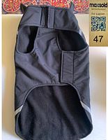 Front view of black dog coat showing two armholes and Velcro closure underside.