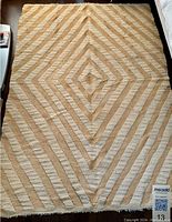 Image of the full rectangular natural rug showing concentric diamond and striped pattern in beige and cream shades.