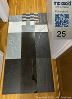 Top view showing arrangement of different sized Italian tile samples including large 12x24 inch tiles in black and gray, smaller rectangular tiles, square tiles, patterned mosaic tiles.