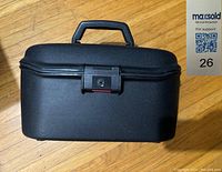 Exterior front view of the black vintage Samsonite makeup case showing the handle, lock, and overall shape.