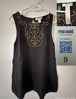 Photo of black sleeveless Kenar blouse with metal embellishments on the front and size tag, front view