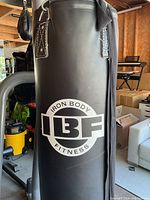 Close view of black synthetic leather heavy punching bag marked Iron Body Fitness