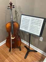 Full view of cello on floor stand next to music stand with sheet music