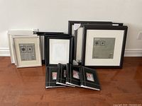 Full collection of black, white, and silver IKEA Virserum photo frames with four small black photo albums in front, displayed on a wooden floor.