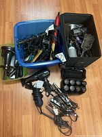 Overview photo of two bins and scattered hair appliances and accessories on floor, showing multiple hair dryers, curling irons, and brushes.