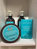 Four Moroccanoil hair care products on shelf: two bottles of Hydrating Styling Cream, one Intense Hydrating Mask jar, and one ChromaTech Service kit box.