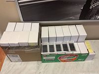 Multiple white boxes stacked beside opened plastic trays of Esteem Lash Clinique eyelash extensions on countertop.