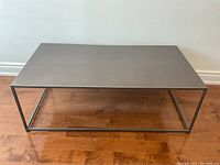 Top-down view of rectangular metal coffee table showing the full surface and structure placed on wood floor.