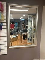 Front view of the rectangular mirror mounted on a wall, showing the reflective glass and frame details.