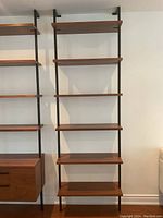 Full view of shelving unit mounted on wall showing six wood shelves on black metal rails