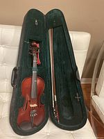 Open hard-shell case displaying violin on left and bow on right