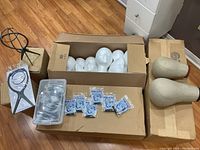 Lot overview showing several styrofoam heads in a box, two fabric-covered heads, packaged wig caps, a metal wig stand, and a plastic container of accessories.