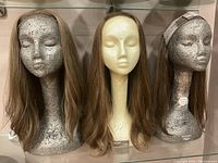 Three wigs displayed on mannequin heads, showing different angles and full lengths.