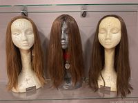 Three wigs on mannequin heads: light brown, dark brown, and medium brown long straight hair wigs.