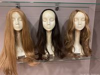 Photo of three wigs on mannequin heads showing front view of different hair colors and styles