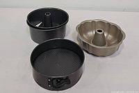 Three Bundt pans and one springform pan shown from overhead on white surface.
