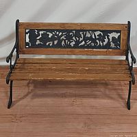 Front view of wooden children's bench with floral metal backrest and wooden slat seat