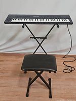 Roland U-20 keyboard with stool and stand setup, keyboard facing forward showing keys.