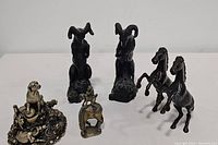 Wide shot showing all six bronze animal statues including the dog, monkey, ram bookends, and horses.