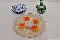 Blue and clear coral bowl, vintage abstract orange and beige plate, and green cut to clear decanter in the background