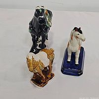 Three porcelain horse figurines viewed from above on a white surface.