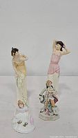 Four Royal Doulton figurines shown together, different poses and colors