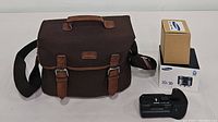 Brown Samsung camera bag with top handle and adjustable shoulder strap, two buckle straps at front, Samsung logo patch.