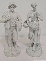 Front view of both white ceramic figurine statues showing details of man and woman statues.