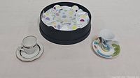 Image showing three espresso cup and saucer sets including the polka dot set, blue and gold set, and colorful bird motif set in the box.