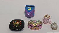 Top view of five trinket boxes including a hinged wedding cake box, crown box, and various floral and cartoon painted boxes.