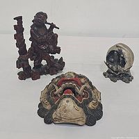 Lot showing all three items together: metal sphere, wooden statue, carved mask