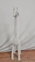 Full side view of the white wicker giraffe sculpture showing the long neck, legs, and overall design
