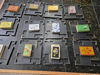 Top view of 12 black Paine's Whist trays each holding one deck of playing cards with various vintage designs.
