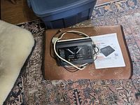 Electronic controller unit of BioMat 7000MX with controls and wiring shown on a brown leather surface with printed manual beside it.