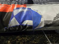 Close-up photo of the original carrying bag with a print showing the folded tent's blue and white dome design and orange details.