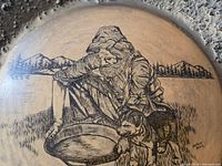 Close-up of prospector and dog artwork on gold pan signed Mukluk Annie