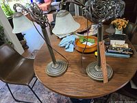 Pair of vintage table lamps on wooden table, showing full view and metal bases with embossed patterns
