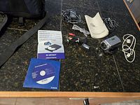 Sony Handycam camcorder and accessories including cables, manuals, battery, and CD laid out on table.