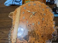 Top view of the burl wood clock showing metal 1 to 12 hour markers with a ruler for size reference.