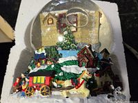 Photo of front view showing detailed horse-drawn carriage, houses, and Christmas decorations on snow globe base.