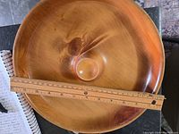 Top view of vintage wooden nut bowl with natural wood grain and ruler for size reference