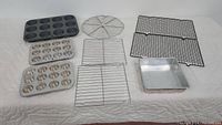 Full set showing three cupcake tins, one cake pan, and four cooling racks arranged on a cloth surface.