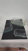 Five clear rectangular glass baking dishes of various sizes displayed on black and white surface.